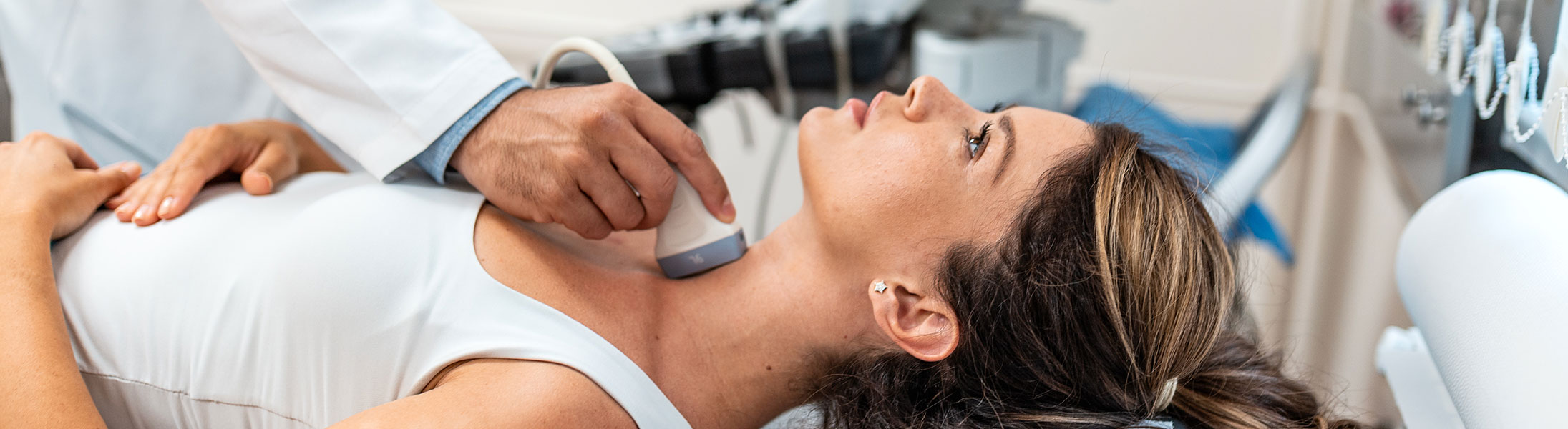 Ärztliche Ultraschalluntersuchung der Schilddrüse bei einer Patientin im Untersuchungsraum.