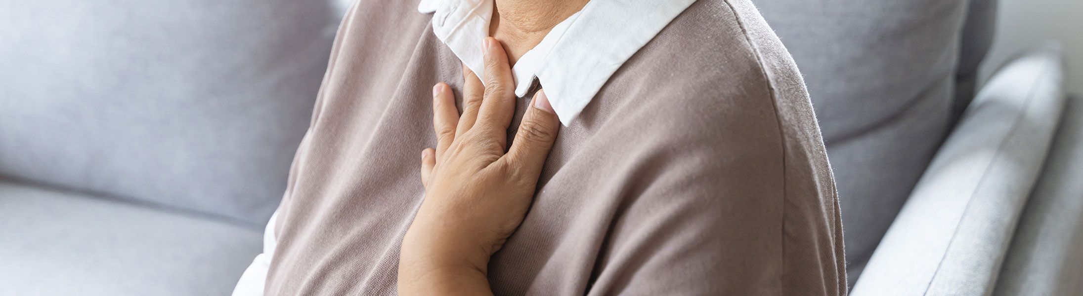 Person mit Beschwerden im Brust- und Halsbereich als Symbolbild für Sodbrennen und Reflux.